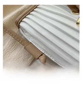 Detailed close-up of white pleated leather texture and brown strap with gold buckles