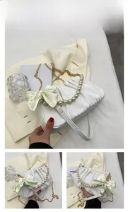 Détail du sac blanc froncé avec poignée en perles et décoration de nœud en soie jaune