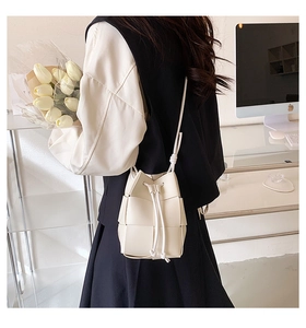 Macro detail of hand-woven cream bucket bag with elegant leather texture and drawstring