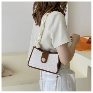 Detail of crossbody bag featuring embossed hearts and silk scarf chain strap on a model