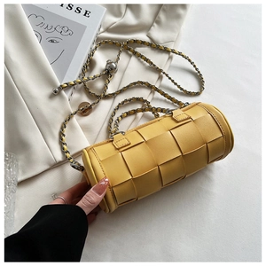 Close-up of yellow woven cylinder bag with adjustable silver chain and metal ball