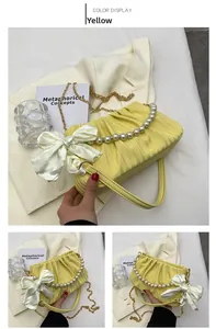 Détail du sac plissé jaune avec chaîne en perles et grand nœud en satin blanc