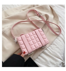 Detailed view of pink textured crossbody bag with silver hardware on beige blazer