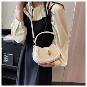 Detail of creamy white crescent handbag featuring golden horseshoe buckle and strap