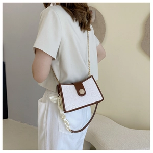 Detail of white PU leather crossbody bag featuring cartoon embossing and silk scarf handle