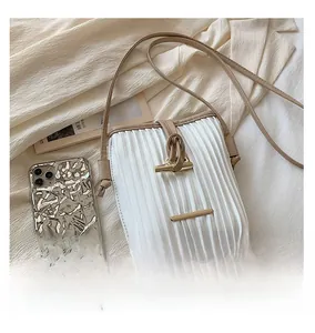Detailed top view of white pleated leather bag with gold buckle on textured background