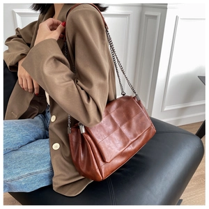 Braune Vintage-Umhängetasche mit Steppmuster und Silberkette am Model präsentiert