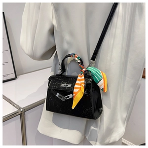 Detail of black embossed Kelly style bag with colorful silk scarf and silver metal lock