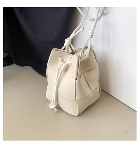 Close-up of off-white leather woven bucket bag with drawstring closure and soft texture