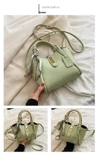 Dettaglio della borsa a secchiello verde con chiusura dorata e foulard decorativo