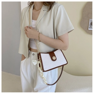 Detail of white embossed crossbody bag with cartoon motifs and decorative silk scarf