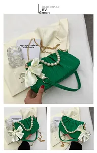 Détail du sac plissé vert avec poignée en perles, nœud satiné et chaîne dorée