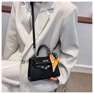 Detail of black embossed leather handbag with silk scarf handle and silver hardware