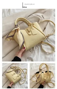 Dettaglio borsa a secchiello gialla con foulard di seta decorativo e chiusura in metallo