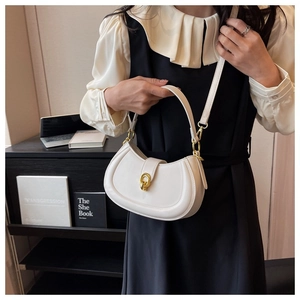 Detail of white crescent bag with gold horseshoe buckle and adjustable strap