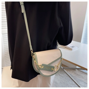 Detail of saddle bag showing beige crocodile pattern leather and sage green strap accents