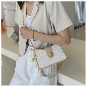 Detail of white baguette bag with cartoon embossing and silk scarf wrap handle