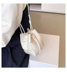 Detail of white woven bucket bag showing wide grid pattern and drawstring closure