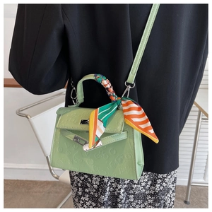 Detail of light green embossed Kelly bag featuring cartoon motifs and silk scarf handle