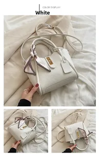 Dettaglio di una borsa a secchiello bianca a grana di litchi con chiusura e foulard di seta