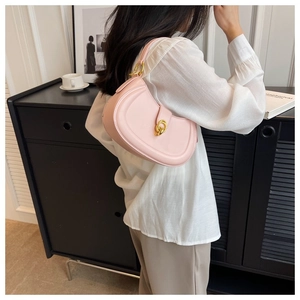 Pink crescent hobo bag with gold ring buckle detail worn by a model in white