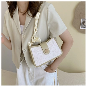 Detail view of cream PU crossbody bag with green trim and silk wrap chain strap