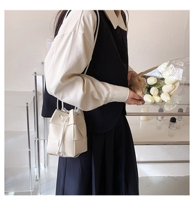 Chic cream woven bucket bag with drawstring closure shown on a model in a minimal setting