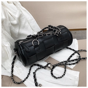 Detail of black woven cylinder bag featuring chunky silver chain and metal ball charm