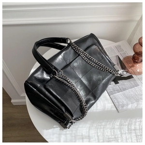 Makroansicht der schwarzen Retro-Ledertasche mit Patchwork-Design und Silberkettenriemen