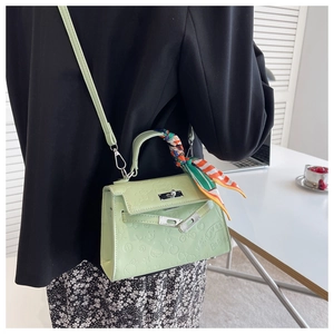 Detail of light green embossed leather Kelly bag with silk scarf and silver twist lock