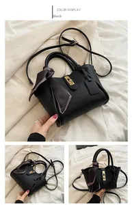 Dettaglio borsa a secchiello in pelle nera con chiusura dorata e foulard di seta
