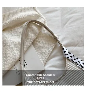 Close-up of beige pleated shoulder bag strap decorated with black and white polka dot scarf