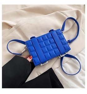 Detail of blue quilted shoulder bag with plaid texture and silver metal hardware