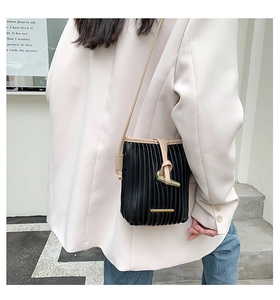 Side view of pleated black crossbody bag with contrast trim on a female model