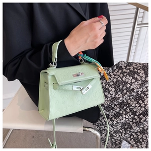 Close-up of light green embossed Kelly style bag with a decorative silk scarf handle