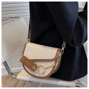 Detail of two-tone saddle bag with crocodile texture and golden hardware on shoulder