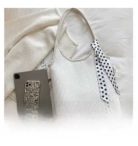 Close-up of white ruched shoulder bag with polka dot scarf detail and fashion tag