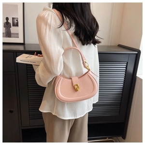 Detail of pink semi-circular leather bag featuring a gold ring clasp and adjustable strap