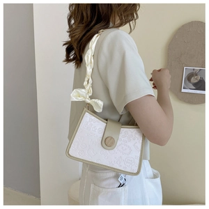 Detail of white mini bag with embossed graffiti, silk bow strap and wood button accent