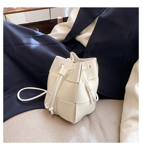 Detail of cream woven leather bucket bag featuring a drawstring closure and fine texture
