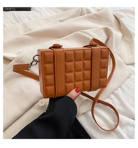 Detail of caramel quilted checkered crossbody bag with silver buckles and thin strap