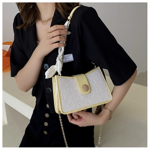 Detail of white handbag with yellow trim, cartoon embossing and decorative silk scarf