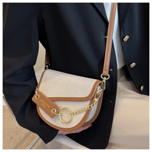 Detail of crocodile pattern saddle bag with contrast stitching and gold ring buckle