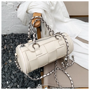 Detail of cream woven cylinder bag featuring silver chain strap and metallic ball charm