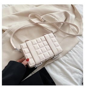 Detail of beige quilted square crossbody bag with adjustable strap and silver metal hardware