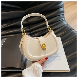 Detailed view of white crescent handbag with gold twist lock on black leather background