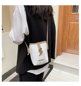 Detailed view of white pleated crossbody bag with golden bamboo buckle on a model
