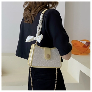 Detail of white embossed leather bag with yellow trim and stylish fabric bow
