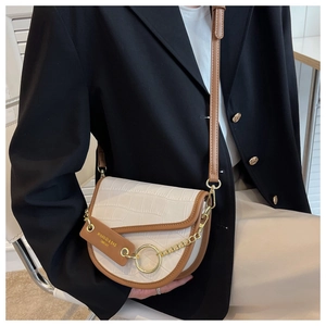 Detail shot of vintage cream faux-crocodile saddle bag with brown leather trim on model