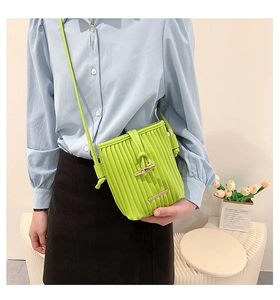 Detail of bright green pleated bucket bag with silver bamboo clasp and shoulder strap